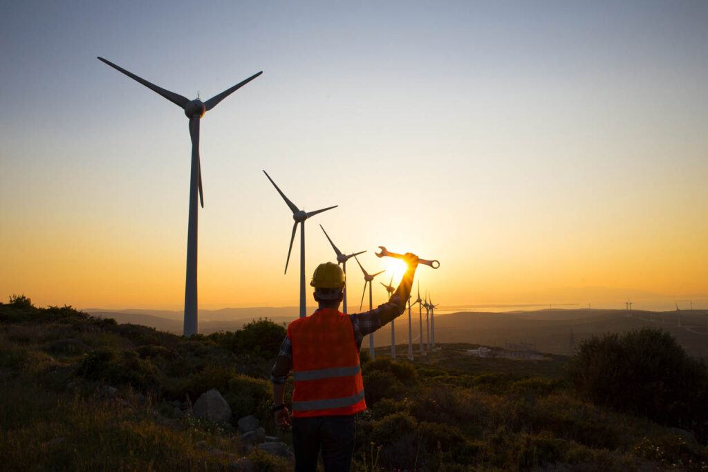 Field engineer in windfarm at sunset.
