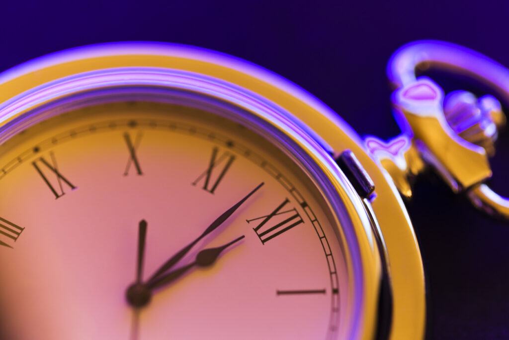 Roman numeral stopwatch on modern purple and orange background, used as hero image for rota vs. roster blog.